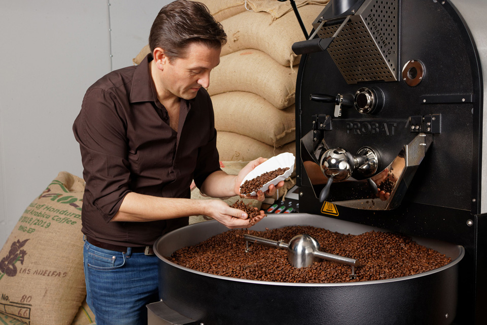 Person schüttet sich für die Endkontrolle Kaffeebohnen in die Hand 